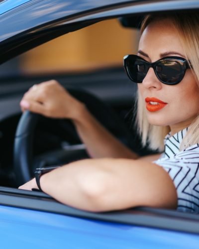 mulher-bonita-e-confiante-em-oculos-de-sol-retrovisor-de-mulher-jovem-e-atraente-em-trajes-casuais-dirigindo-um-carro